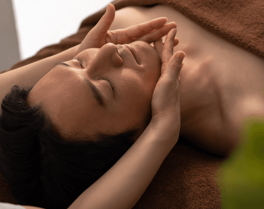A man relaxing during a professional facial treatment, with a therapist gently holding his face