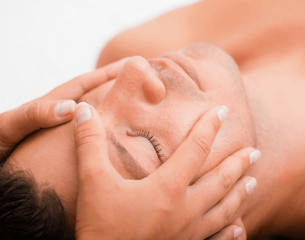 A man receiving a relaxing facial massage with closed eyes, highlighting a calming skincare treatment