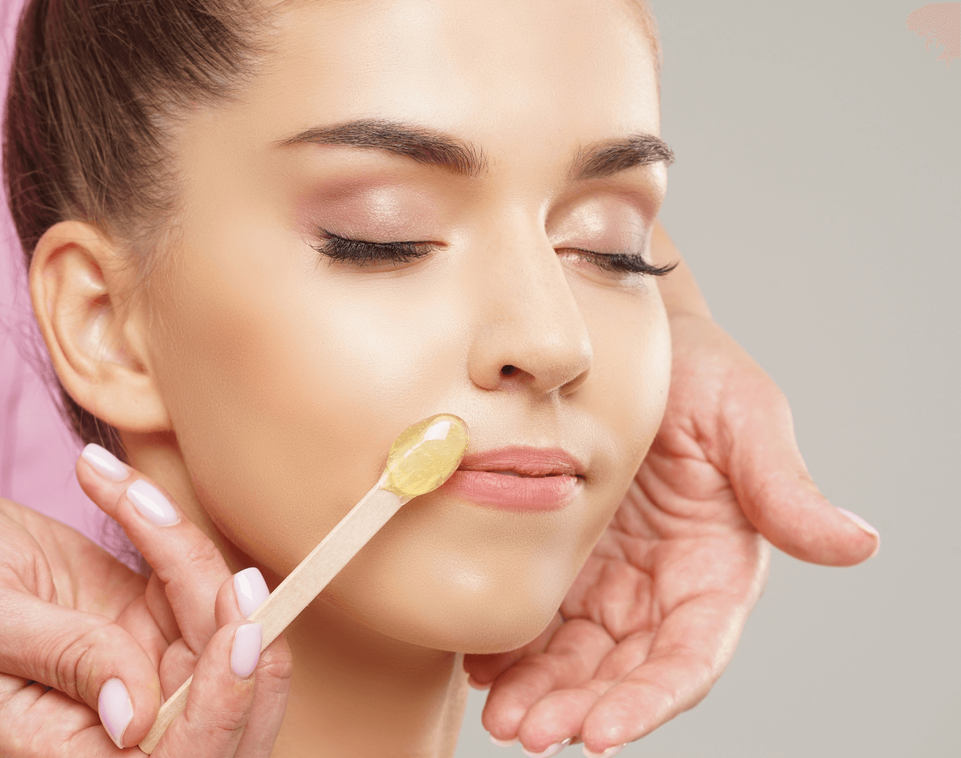 Close-up of a woman receiving lip wax treatment with warm wax applied above the upper lip using a wooden spatula, ideal for promoting lip and chin waxing services.
