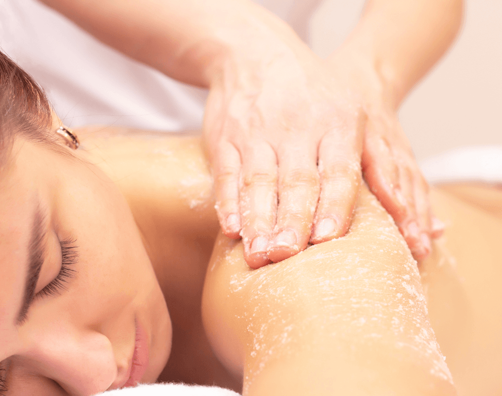 Close-up of exfoliating treatment being applied to a woman’s back during a herbal cleanse