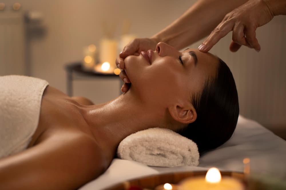 Woman enjoying a calming facial treatment at The Beauty Spot in Wadebridge, surrounded by soft candlelight in a serene spa setting.